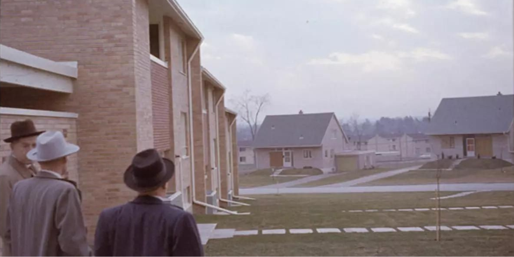 Three men in fedoras looking out at a housing development