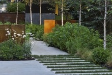 Weathering metal mesh screens with integrated lighting provide syncopated structural elements along the front walkway