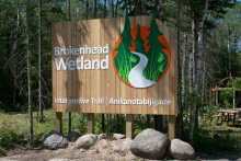 Brokenhead Wetland Interpretive Trail site welcome sign in parking lot area.
