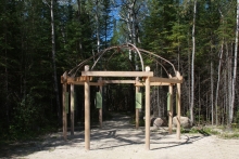 "Wigwam" Trailhead Structure featuring cedar posts and beams with elevated cedar trunk canopy and interpretive signage.